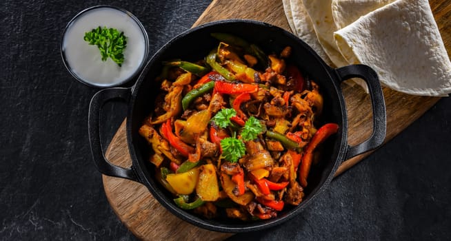 Fajita with stripped peppers and onions served on a hot iron skillet