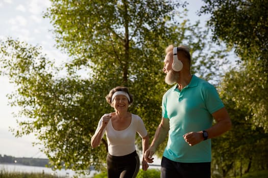 Senior man flirting with pretty elderly woman during morning jogging. Romantic date on training workout