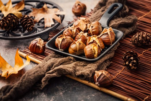 Roasted chestnuts in iron pan  on old kitchen table