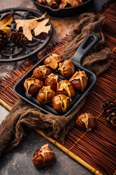 Roasted chestnuts in iron pan  on old kitchen table