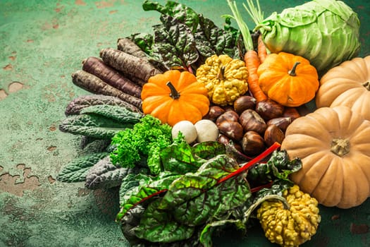 Organic raw autumn and winter vegetables on kitchen table with carrots, chesnuts, chard, kale
