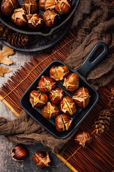 Roasted chestnuts in iron pan  on old kitchen table