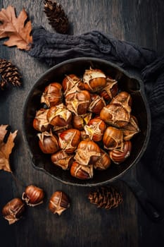 Roasted chestnuts in iron pan  on old kitchen table