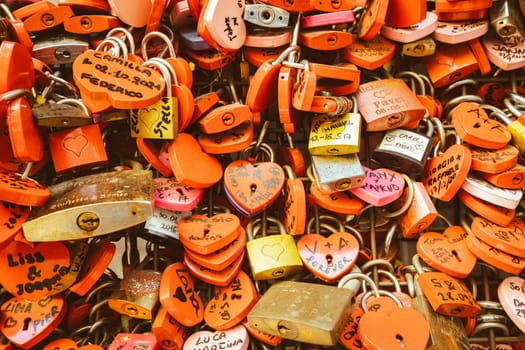 Verona, Italy - June 2022: background of heart-shaped locks on a wall, symbol of love forever