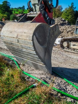 Wide angle close-up view of a lowered excavator bucket on a construction site in Bavaria.