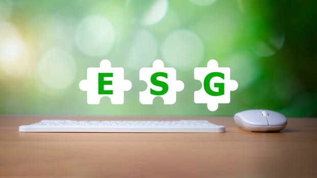 Keyboard and mouse placed on a wooden background with letters printed on a white Jigsaw icon representing ESG concepts for environmental, social and governance, business environmentally responsible.