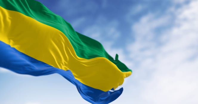 National flag of Gabon waving in the wind on a clear day. Three equal horizontal bands of green, yellow, and blue. 3d illustration render. Fluttering fabric