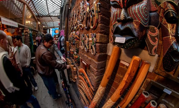 London, United Kingdom - March 31, 2007: Unknown shoppers looking at goods (Aboriginal musical instruments) at Camden Lock, famous market at UK capital. Extreme wide perspective fisheye photo.