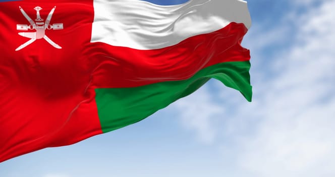 National flag of Oman waving in the wind on a clear day. Vertical red stripe with Oman emblem and three horizontal stripes: white, red, and green. 3d illustration render. Rippling fabric