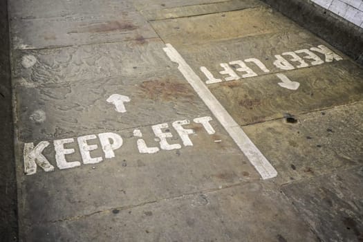 KEEP LEFT written on asphalt ground in pedestrian tunnel pathway