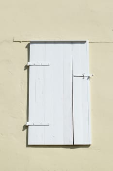 Old white shutter and window made of wood on a light house wall, Germany