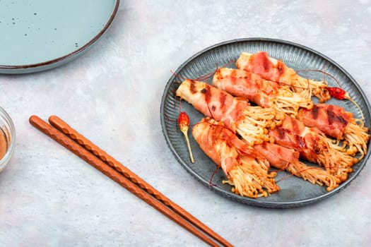 Enoki mushrooms appetizer fried in bacon. Bacon and enoki mushroom roll. Asian cuisine