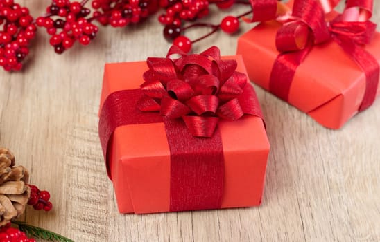 A box with a gift wrapped in red paper with a bow on the table