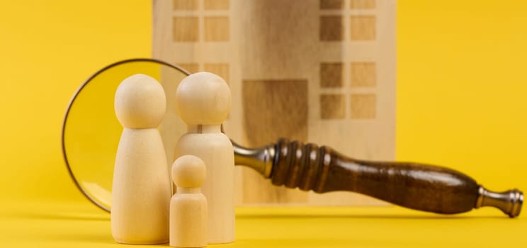 Magnifying glass and a family of wooden figures on the background of a house, the concept of searching for real estate rental, mortgage