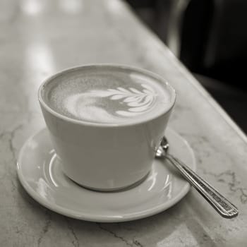 Black and white picture of a cup of latte macchiato in a cafe in the old town of Prague