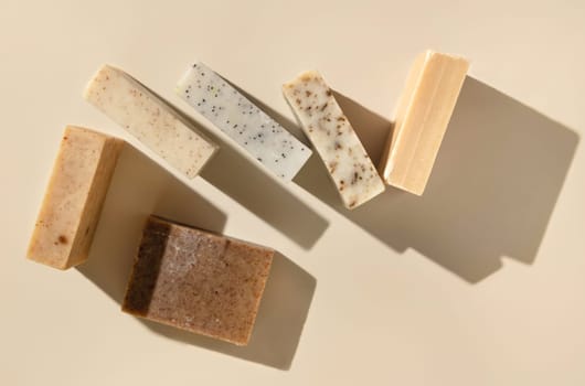 Natural herbal beige and brown handmade soap bars on light beige top view, hard shadows. Hygiene products for Spa and skin care. Using organic handmade sopas in everyday routine