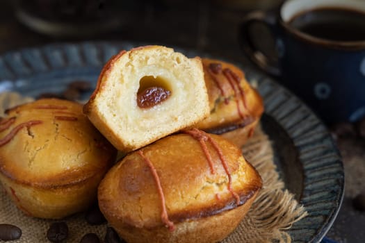 Pasticciotto leccese pastries on a dark blue plate near coffe cup on dark table, typical apulian breakfast, close up. Table decorated with coffee beans