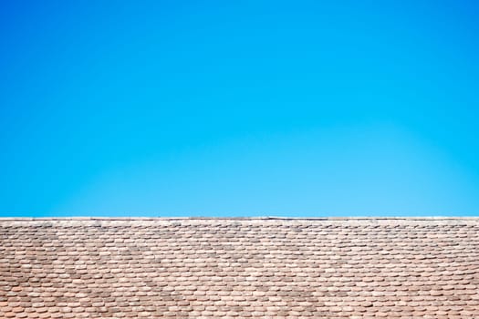 Old tiles on roof and flat blue sky background.