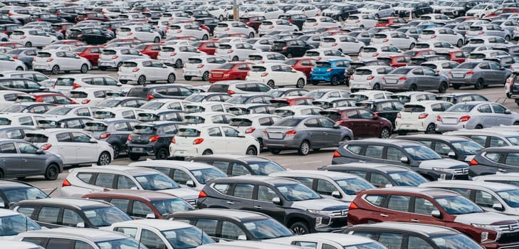 Lamchabang, Thailand - July 02, 2023 A distribution center in a sunny car factory houses rows of new cars. A top view reveals a bustling parking lota symbol of modern manufacturing and technology.