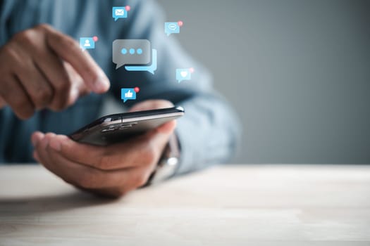 Home office setup man engages smartphone, typing for live chat and social network concepts. Chat box icons emerge, symbolizing digital communication and social media marketing.