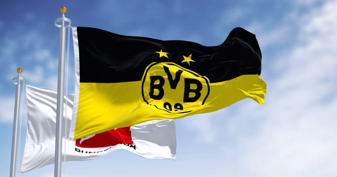 Dortmund, DE, Nov. 10 2023: Borussia Dortmund flag waving with Bundesliga flag on a clear day. Professional german football club. Illustrative editorial 3d illustration render. Rippling fabric