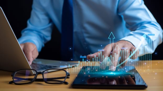 Businessman taps his finger on his tablet to display a graph with arrow for the future growth plan of his organization. finance, management, plan, management, strategy