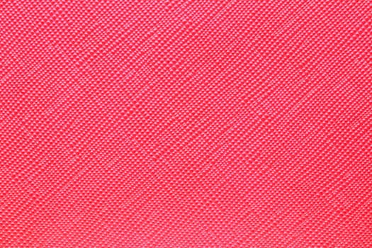 Seamless plastic texture background. Close-up of a detail from a red surface of a cosmetic bag. Beautiful backdrop. Macro.