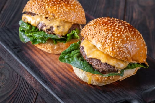 Two homemade cheeseburges on the wooden background