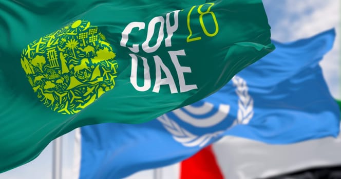 Dubai, UAE, Nov. 30 2023: Flags of COP28, UNFCCC and UAE waving on a clear day. 3d illustration render. Selective focus. Rippling fabric