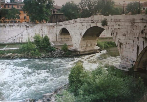 A stone arch bridge leads across the Tiber in Rome