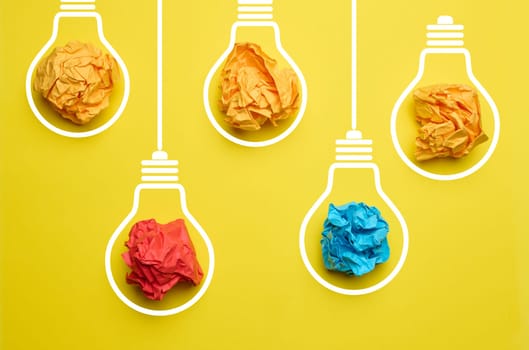 Crumpled balls of paper inside an electric lamp on a yellow background. Concept of new ideas, brainstorming