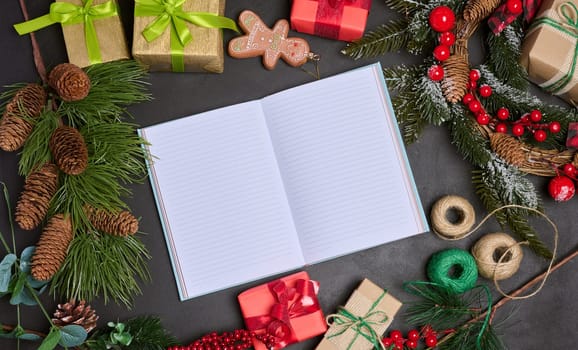 Open notebook with blank sheets on the table in the middle of Christmas decor, top view
