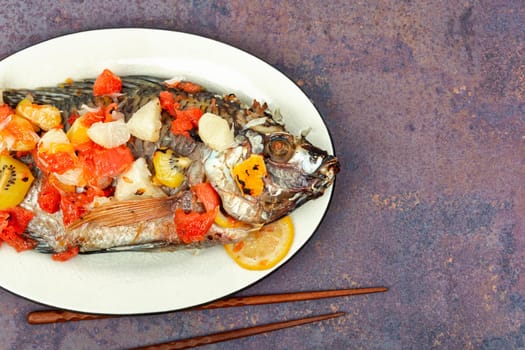 Grilled tilapia fish with fruit in white plate. Healthy food concept. Asian food.