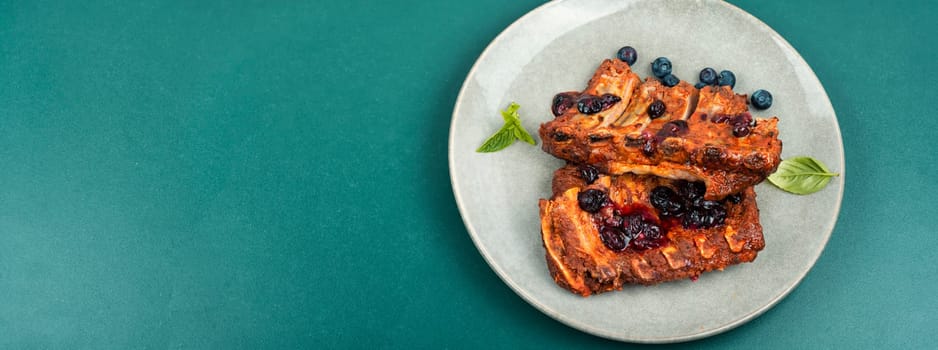 Delicious fried pork ribs with blueberry sauce. Restaurant menu. Space for text.