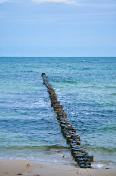 Groynes jut out into the Baltic Sea. Wooden trunks to protect the coast. Landscape from the sea