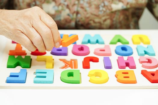 Asian elderly woman playing puzzles game for treatment dementia prevention and Alzheimer disease.