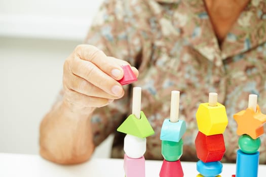 Asian elderly woman playing puzzles game for treatment dementia prevention and Alzheimer disease.
