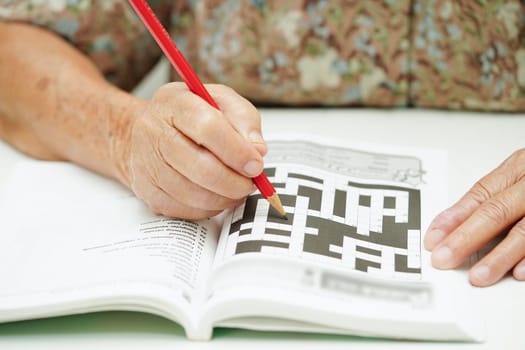 elderly woman playing sudoku puzzle game for treatment dementia prevention and Alzheimer disease.