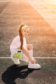 Girl jogging on a sunny summer evening, laying on treadmill, stadium, physical training, back to school, tired.