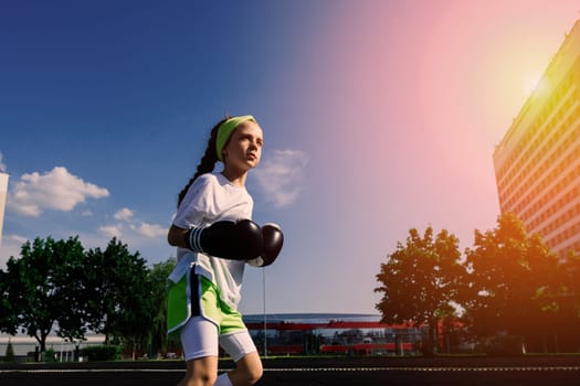 Female child boxer in gloves, feminism concept. Back to school, physical training.