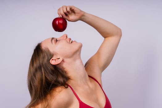 Cropped of sporty female with well fit body holding an apple, healthy food and fit body concept