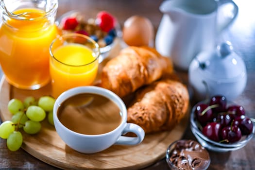 Breakfast served with coffee, orange juice, egg, cereals and croissants.