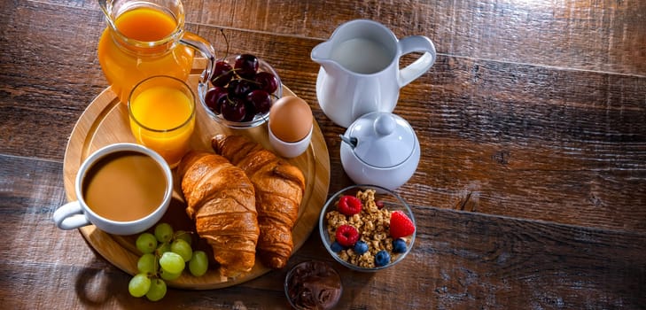Breakfast served with coffee, orange juice, egg, cereals and croissants.