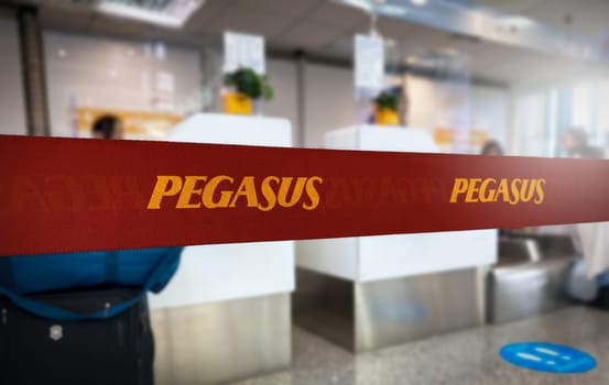 Istanbul, TR, 30 Nov. 30 2023: Vibrant red queue divider with Pegasus Airlines branding in bold yellow letters, prominently displayed in a blurred airport check-in area