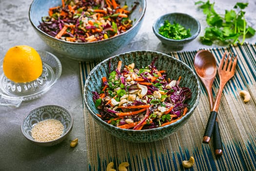 Red cabbage salad in Asian style with carrots, cilantro, cashew nuts and onions