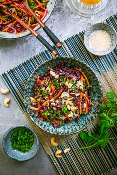 Red cabbage salad in Asian style with carrots, cilantro, cashew nuts and onions