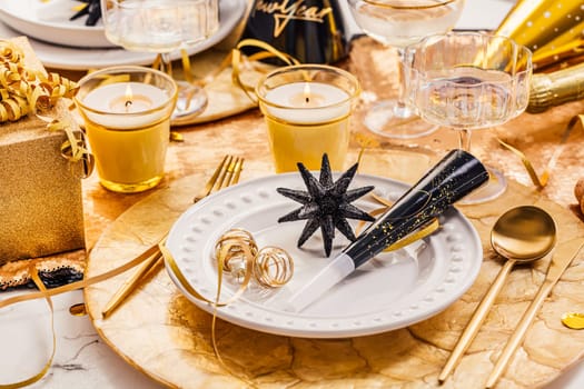 New Years Eve celebration. Holidays served table with champagne and and luxury golden cutlery, with decoration and Christmas decor