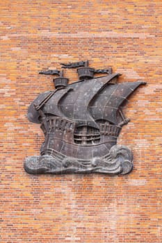 Sailing ship made of metal, on a wall with red bricks