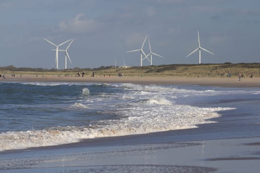 several wind turbines, with beach and the sea in the foreground
