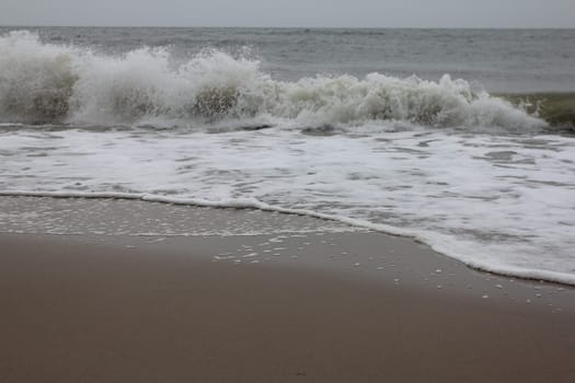 Waves with white crests inundate the sandy beach